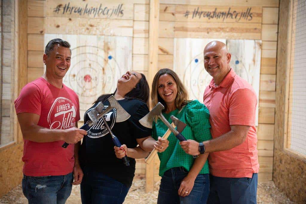 Image of the couple owner along with another couple holding axes while posing for a picture at Throw Lumber Jills' axe-throwing lanes - www.jills.cloudsend.us