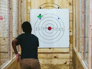 Image of a kid throwing an axe on the target board at Throw Lumber Jills